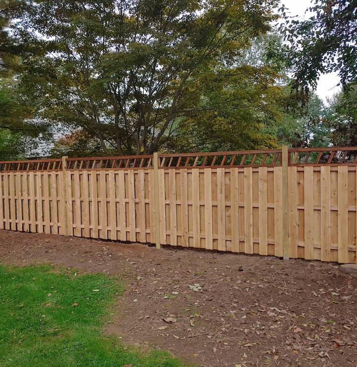 Wood fence with a decorative lattice top following a yard line