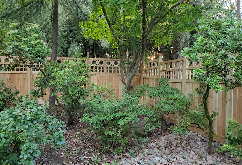 Decorative wood fence with circular top details in a landscaped setting
